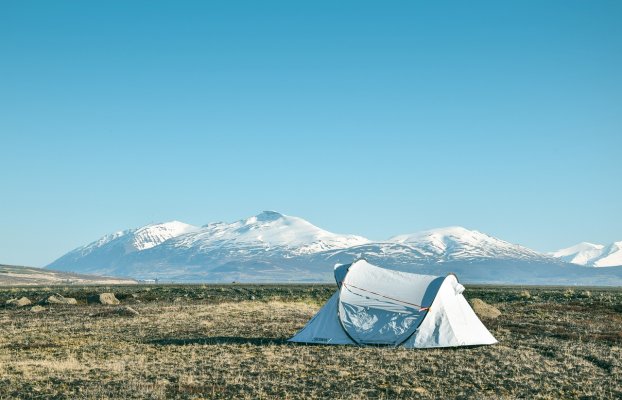 tent setup outside on an open field with mountains in the backdrop